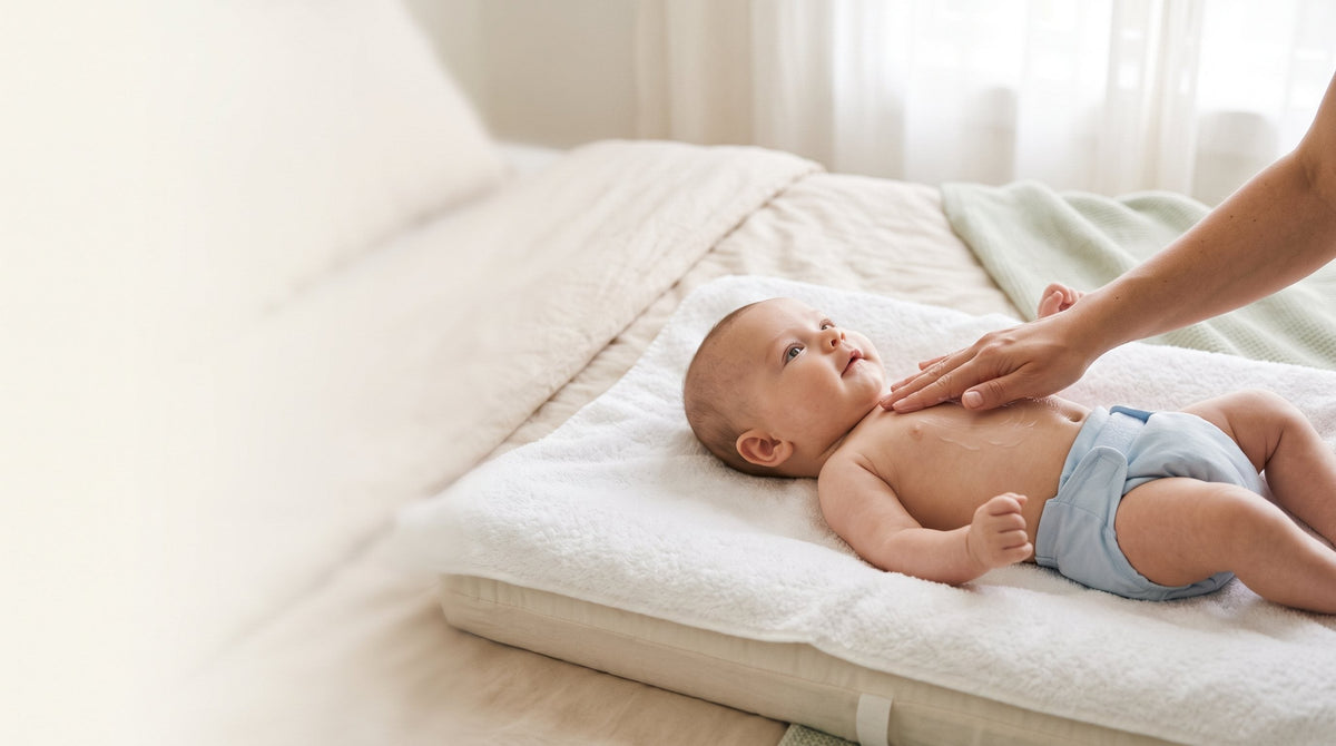Parent gently applying lotion to a smiling baby on a soft towel