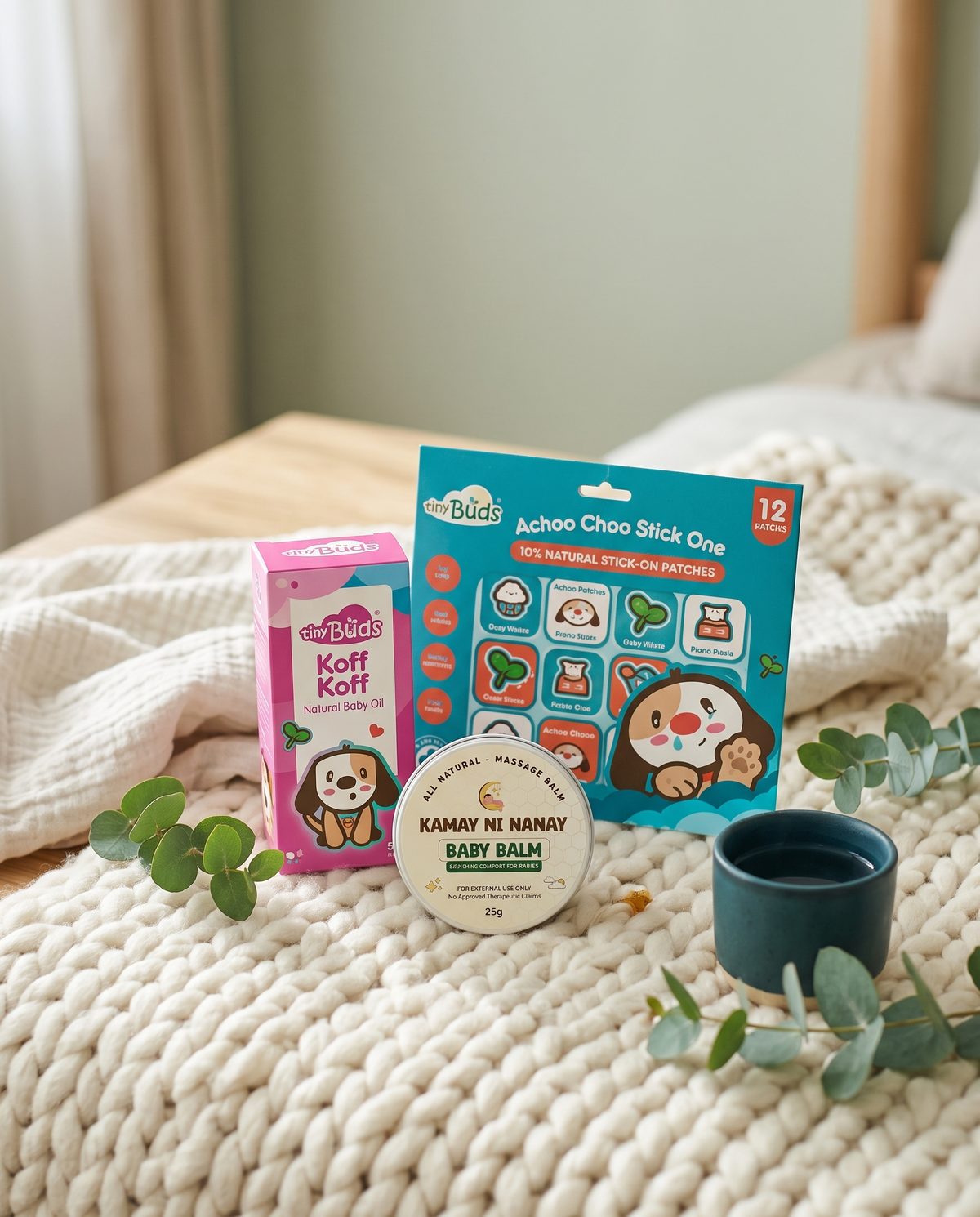 Baby balm, chest oil and nasal relief patches on a knitted blanket with eucalyptus