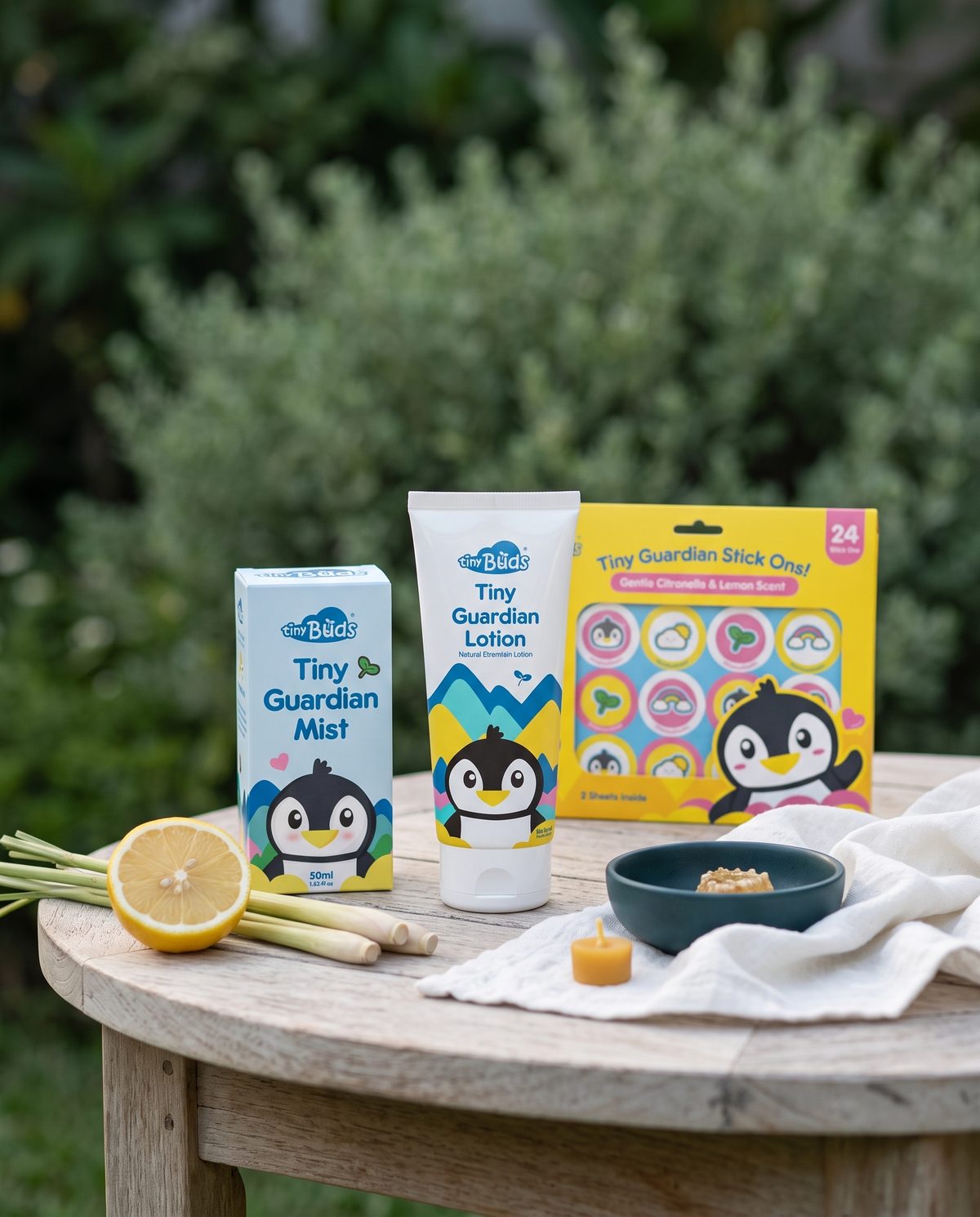 Tiny Guardian natural insect repellents on a garden table with lemongrass and lemon